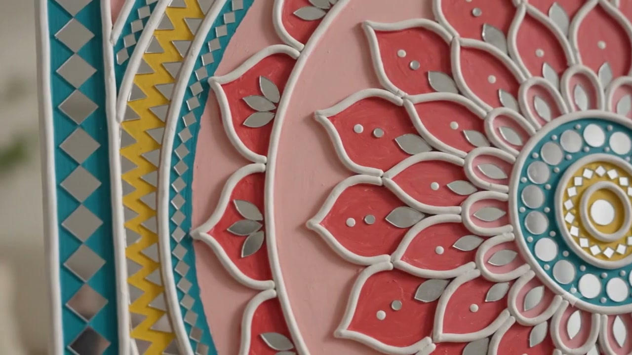 Raised clay Lippan mandala with coral petals, teal border, and inset mirrors