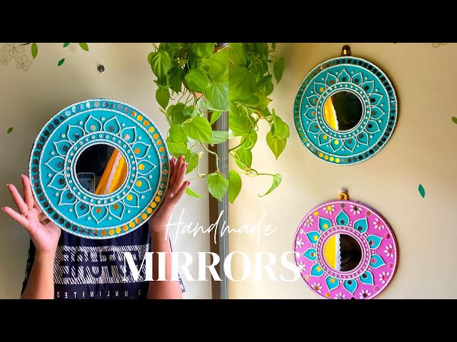 Finished circular Lippan mirrors in teal and pink on a wall
